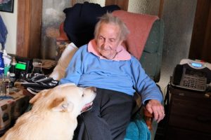An older woman living independently in her own home, petting her dog.