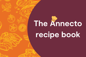 Orange background with various drawings of food. Text in purple bubble that reads "The Annecto recipe book"